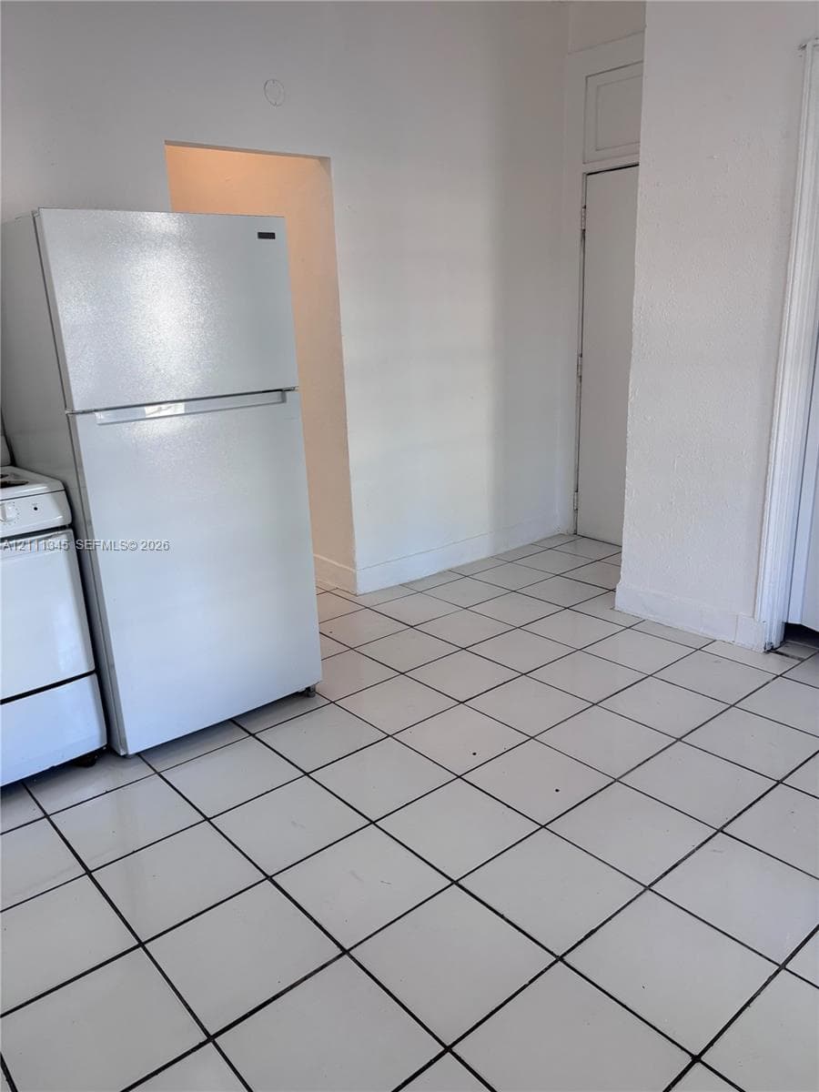 Kitchen area featuring white ceramic tile flooring and a top-freezer refrigerator