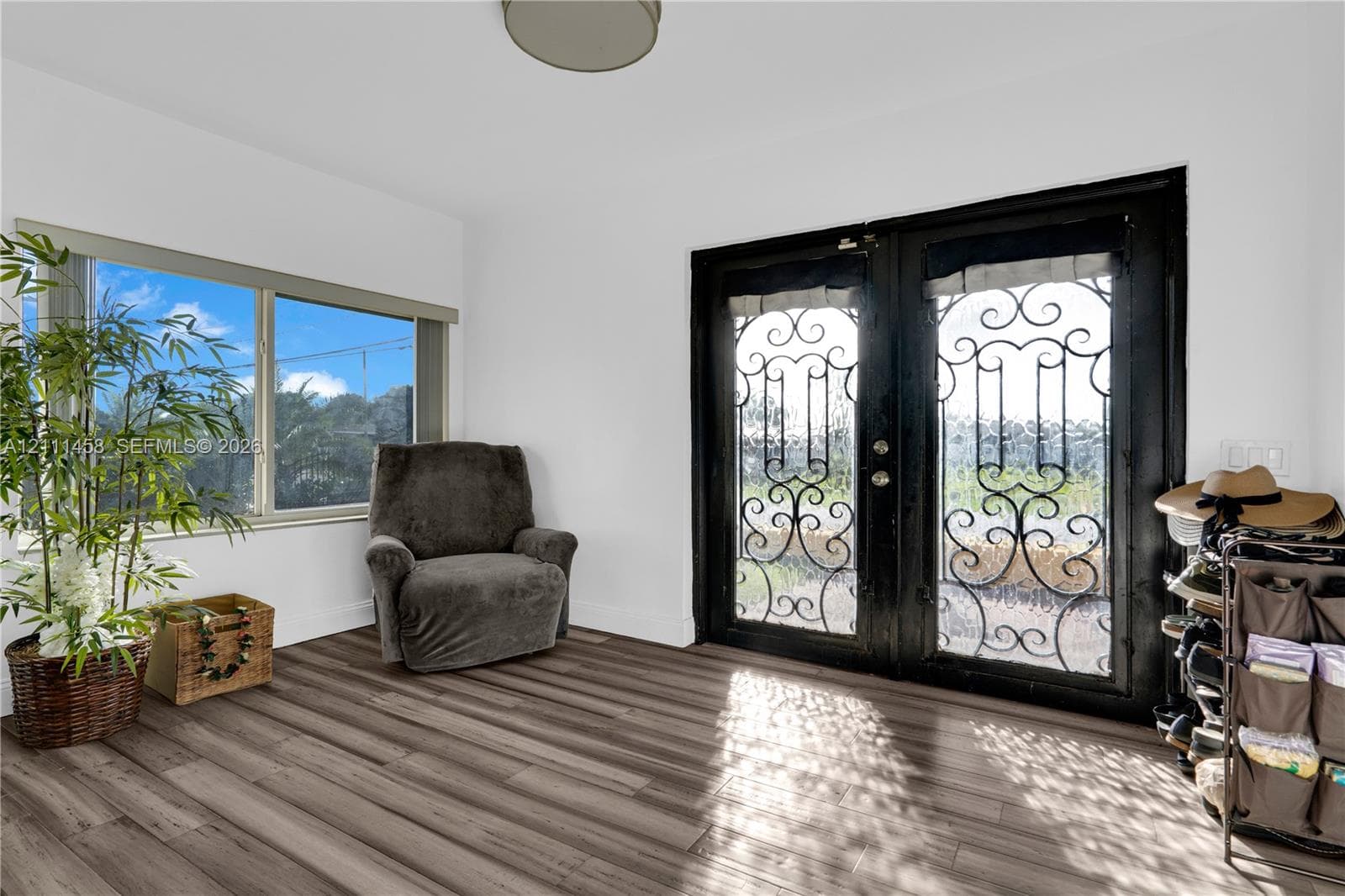 Double entry doors featuring decorative black iron grillwork, wood-finish flooring, and a large horizontal window