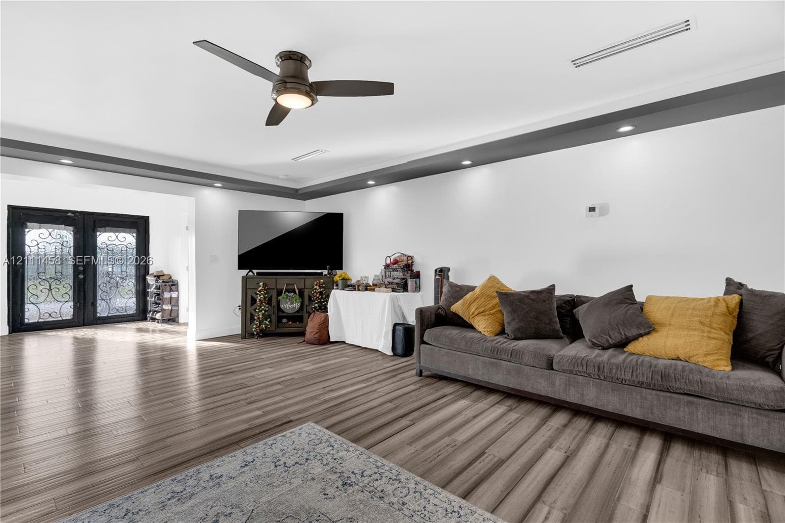 Open-concept interior, tray ceiling with recessed lighting, and double entry doors with decorative iron detailing
