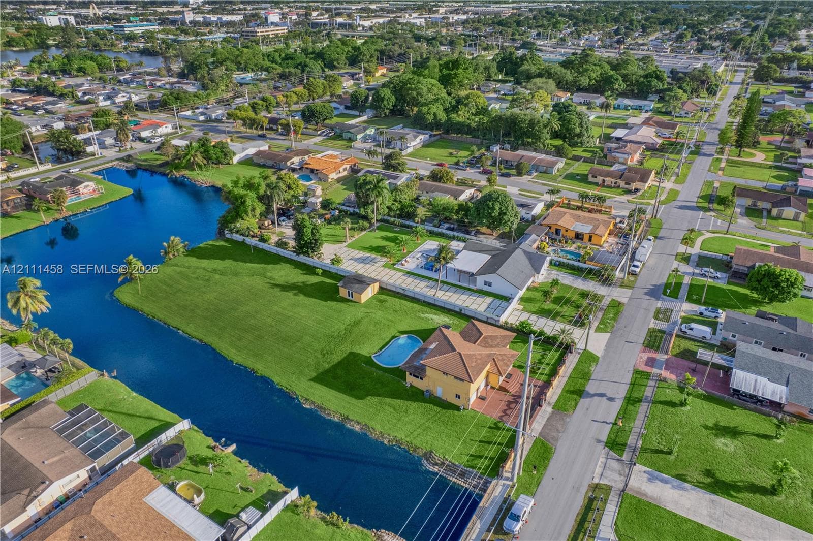 Waterfront property featuring a canal-side lot, private swimming pool, expansive lawn, and concrete-tile roofing