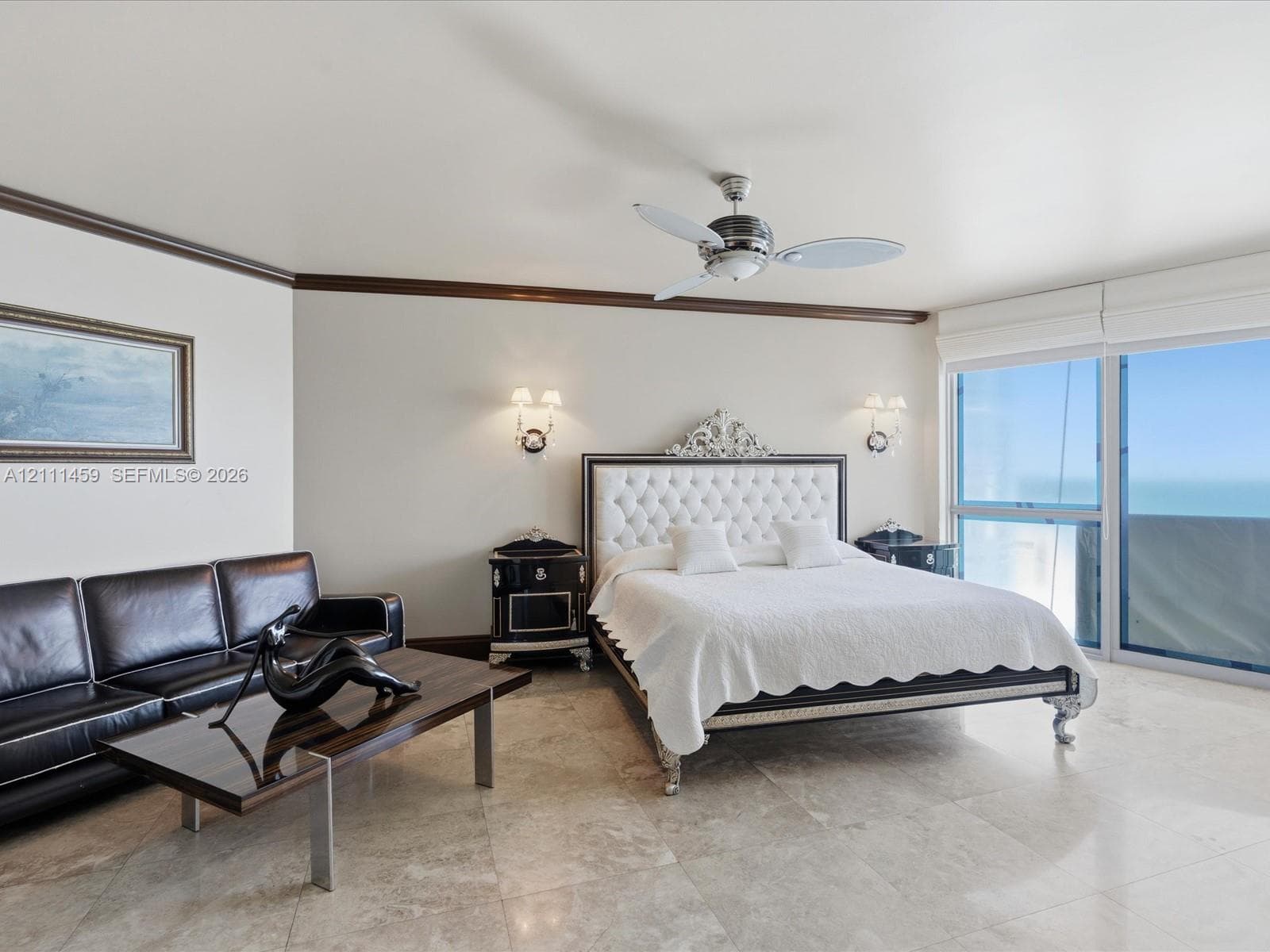 Polished stone flooring, crown molding, multi-blade ceiling fan, wall-mounted light fixtures, and floor-to-ceiling glass sliding doors