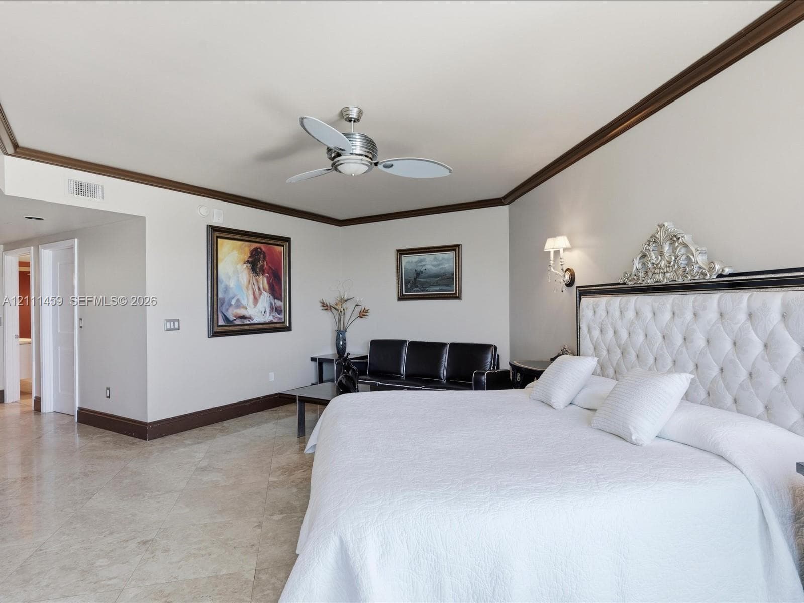 Large room featuring stone flooring, crown molding, wall-mounted light fixtures, and a ceiling fan with integrated lighting
