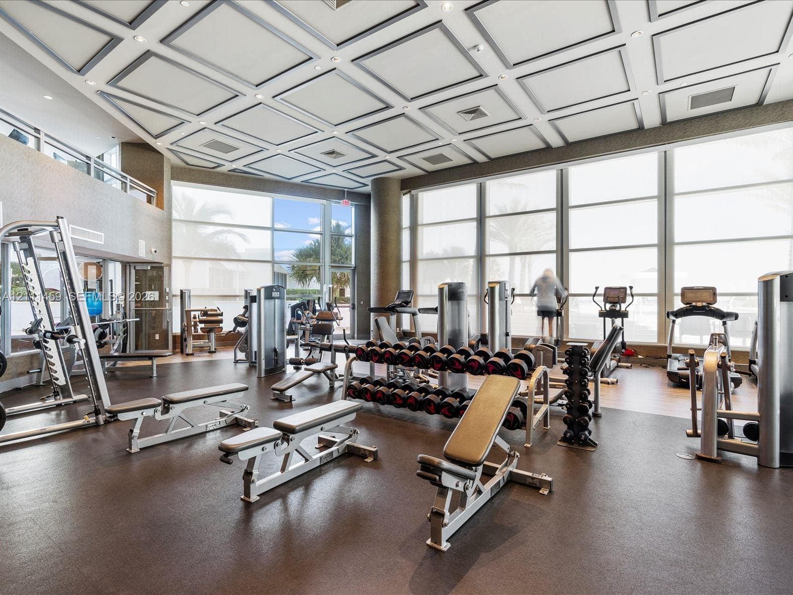 Fitness center featuring a coffered ceiling, floor-to-ceiling windows, and impact-resistant rubber flooring