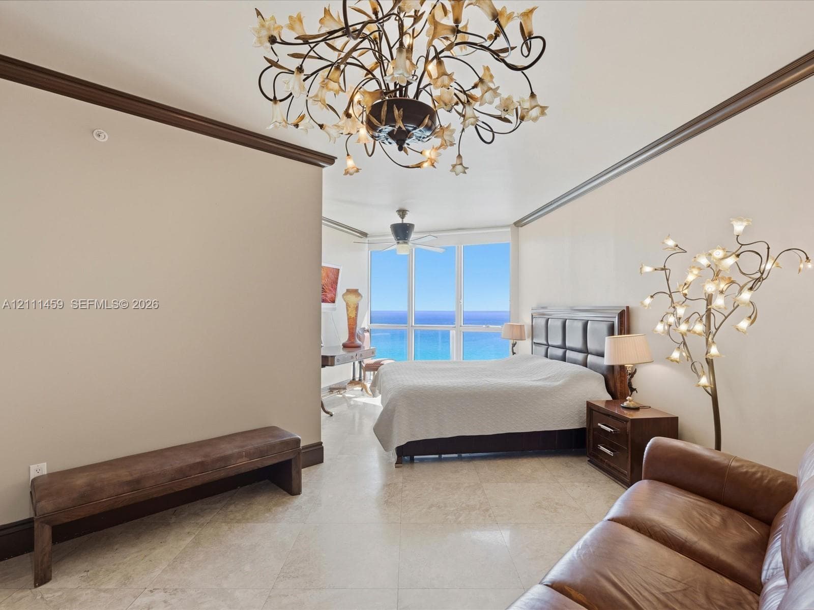 Floor-to-ceiling windows, polished stone flooring, intricate floral-style chandelier, and crown molding