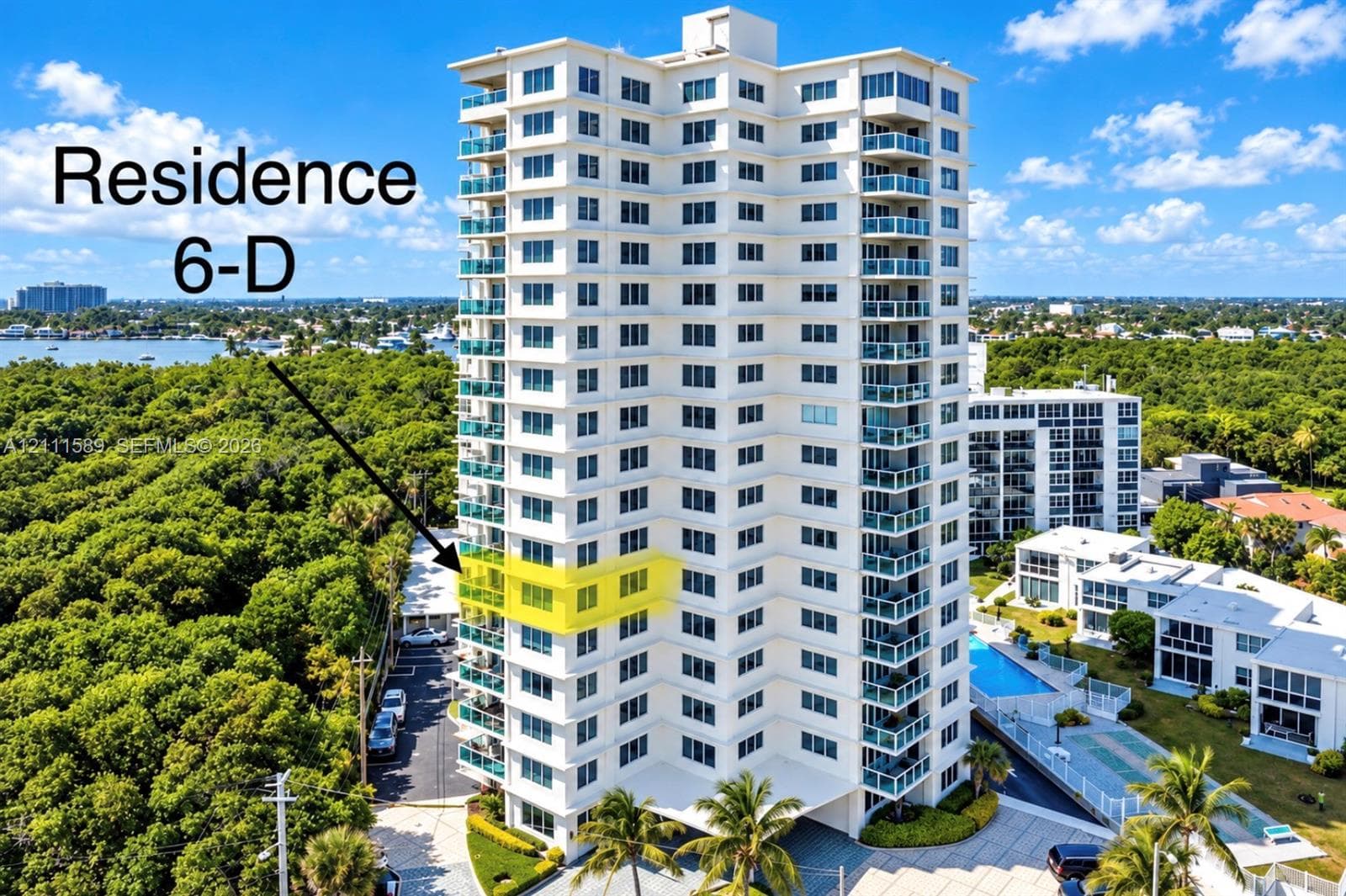 High-rise residential building featuring private balconies with glass railings, an exterior swimming pool, and dedicated paved parking