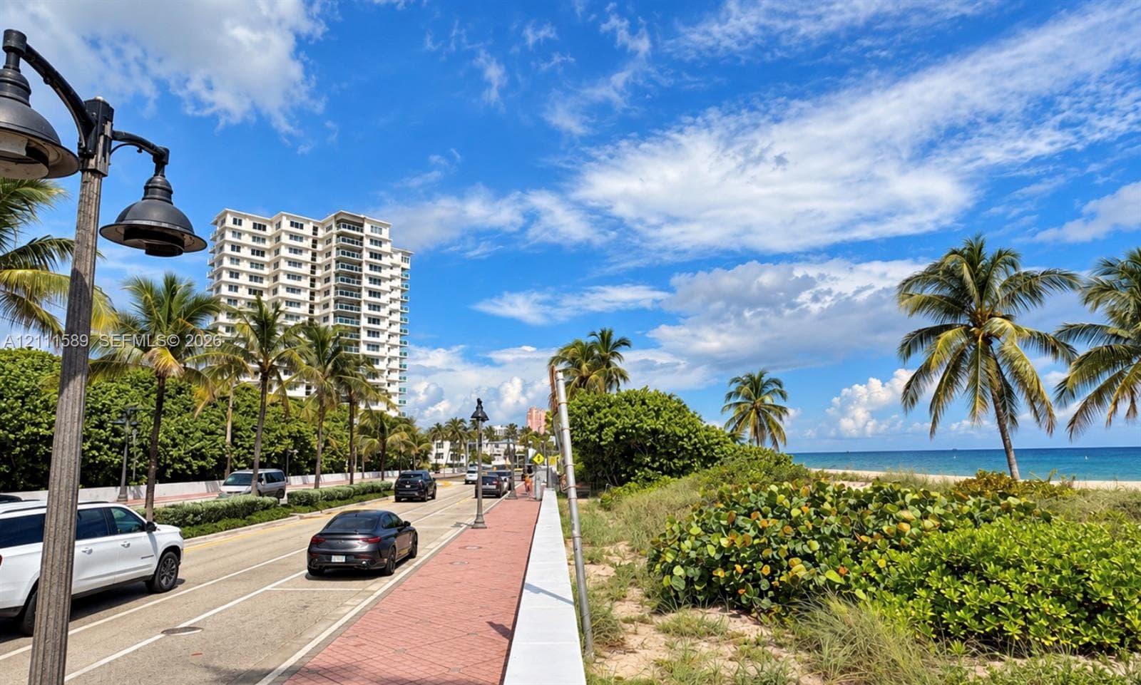 Coastal location featuring brick-paved sidewalks, dark-finish metal street lamps, and tropical landscaping along the shoreline
