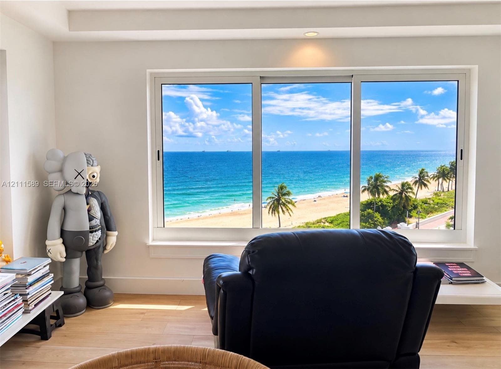 Large, multi-panel window featuring a coastal backdrop, wood-finish flooring, and recessed ceiling lighting