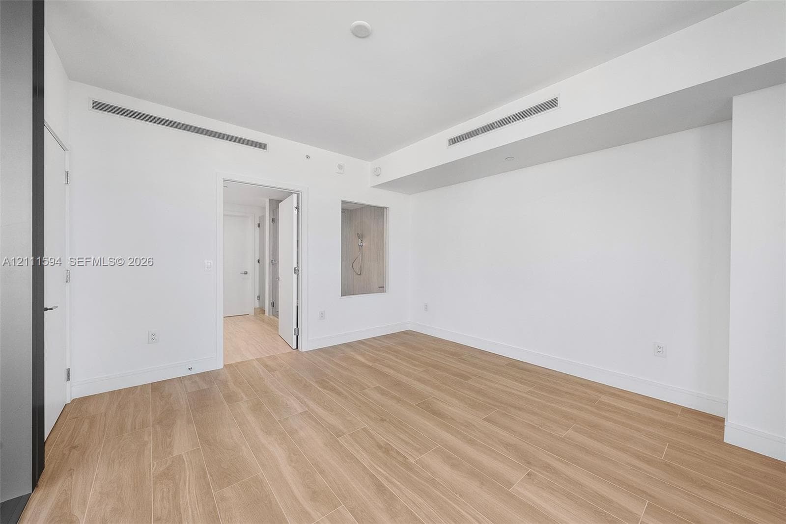 Minimalist interior featuring wood-finish flooring, recessed ceiling lighting, and a square wall niche