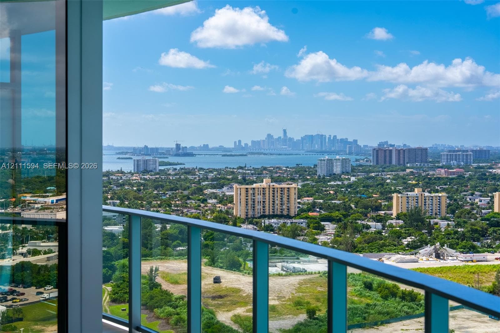 Expansive terrace with floor-to-ceiling glass paneling and a metal railing, providing a panoramic cityscape and water horizon