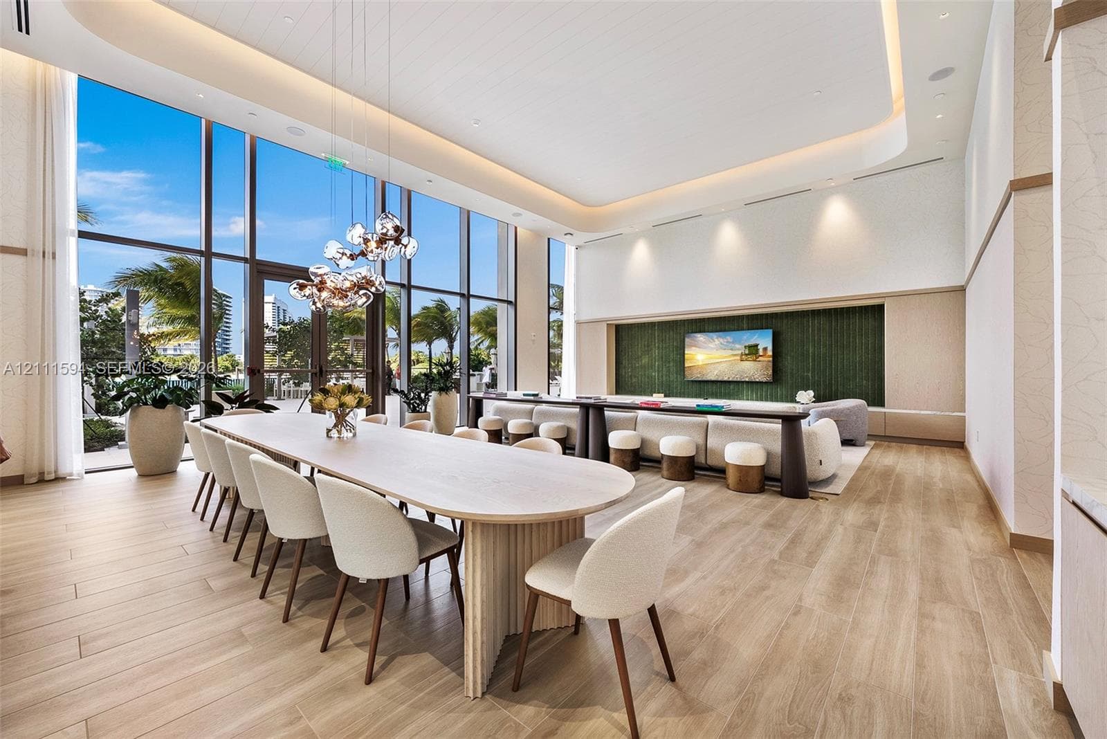Expansive room featuring floor-to-ceiling windows, wood-finish flooring, recessed cove lighting, and a green textured accent wall with integrated cabinetry