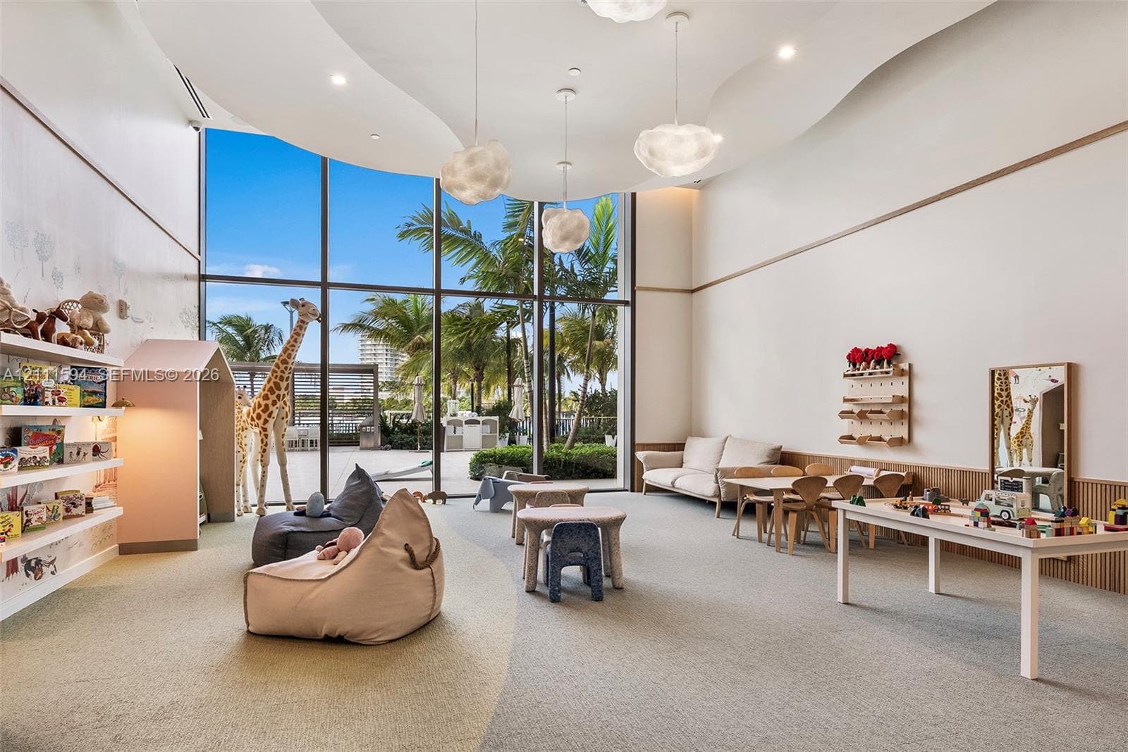 Floor-to-ceiling windows, custom sculpted ceiling with recessed lighting, integrated wall shelving, wood-paneled wainscoting, and suspended contemporary light fixtures