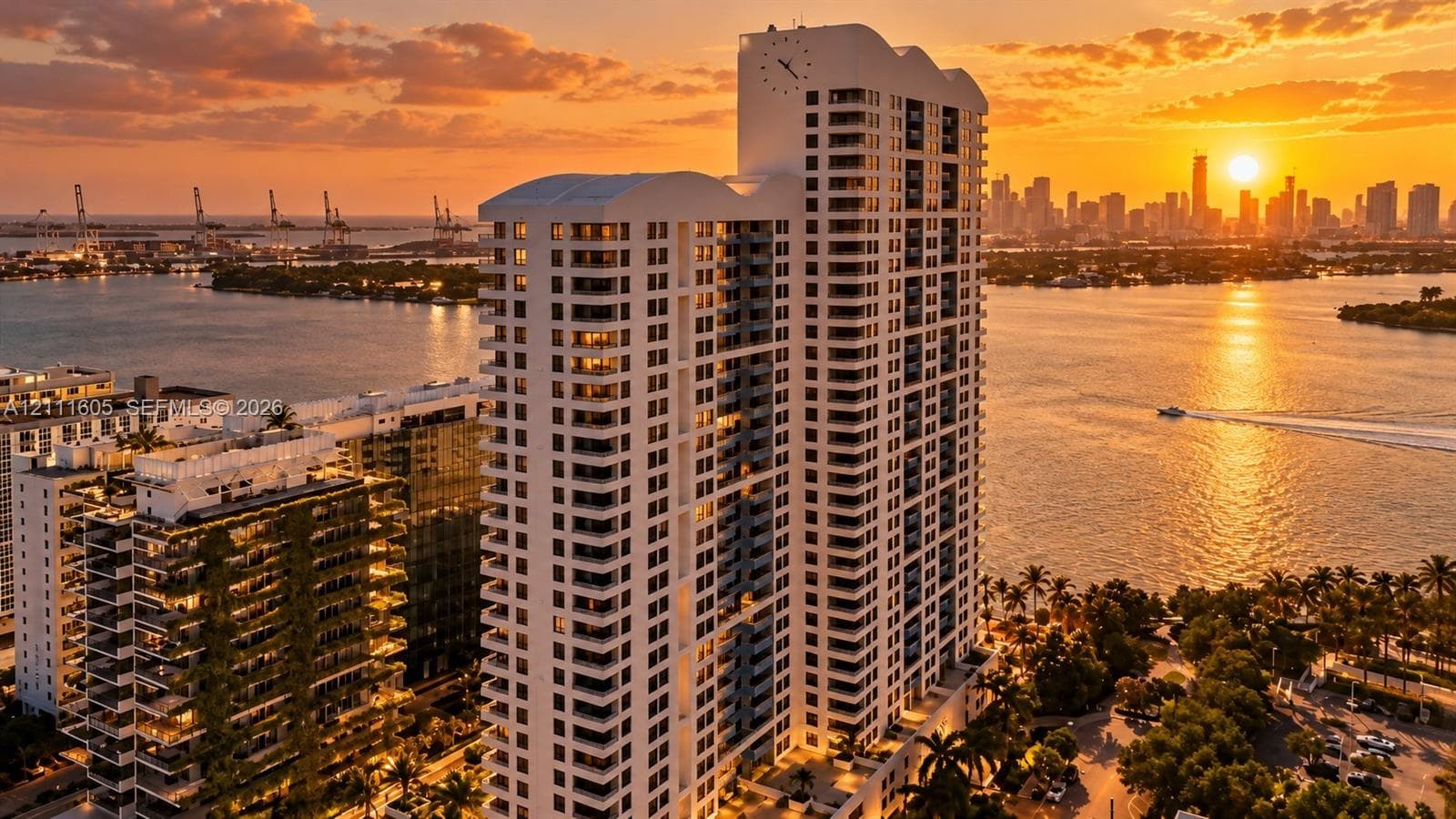 High-rise residential tower featuring a prominent integrated clock face, uniform balcony grid, and water-fronting orientation