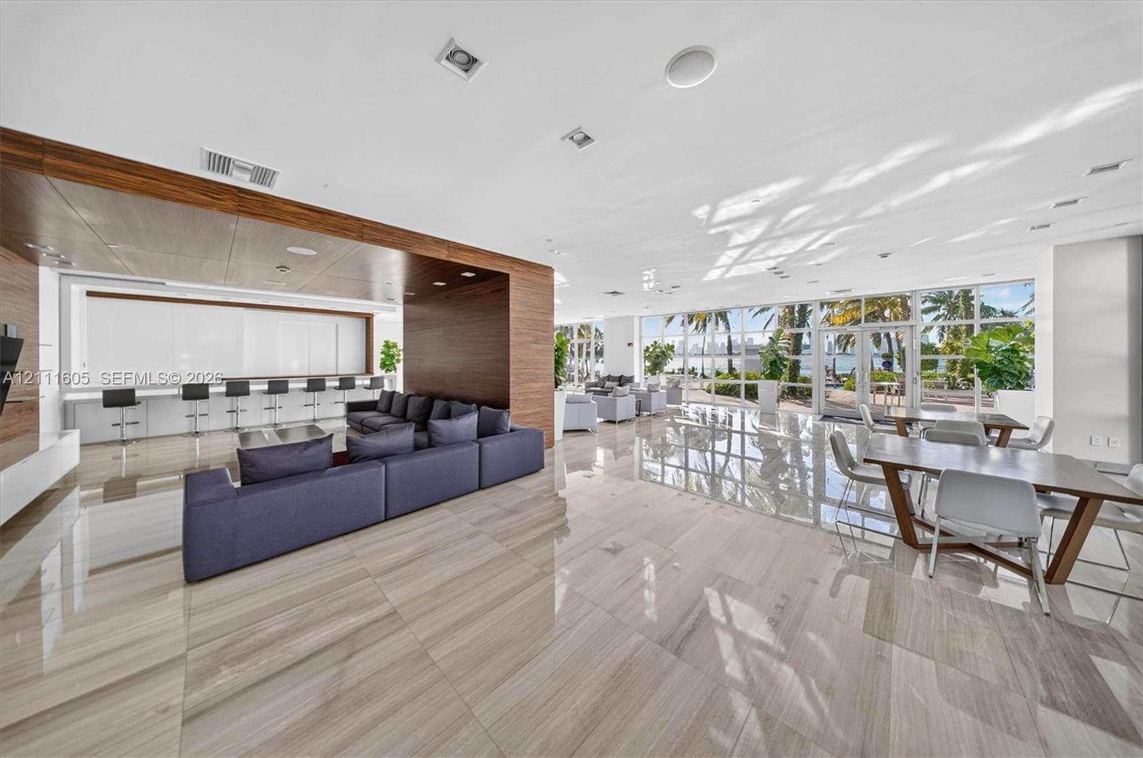 Expansive interior featuring large-format tile flooring, wood-paneled accent walls, integrated recessed lighting, and floor-to-ceiling glass windows