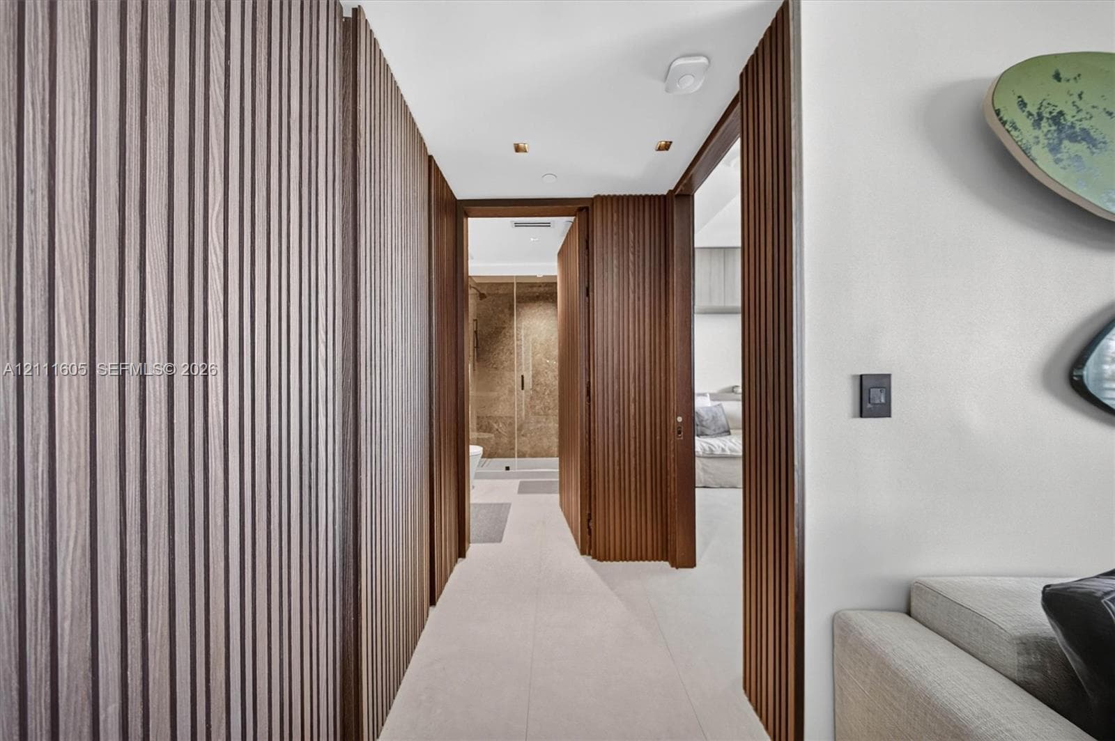 Vertical wood-slat wall paneling, flush-mount ceiling lighting, and large-format tile flooring