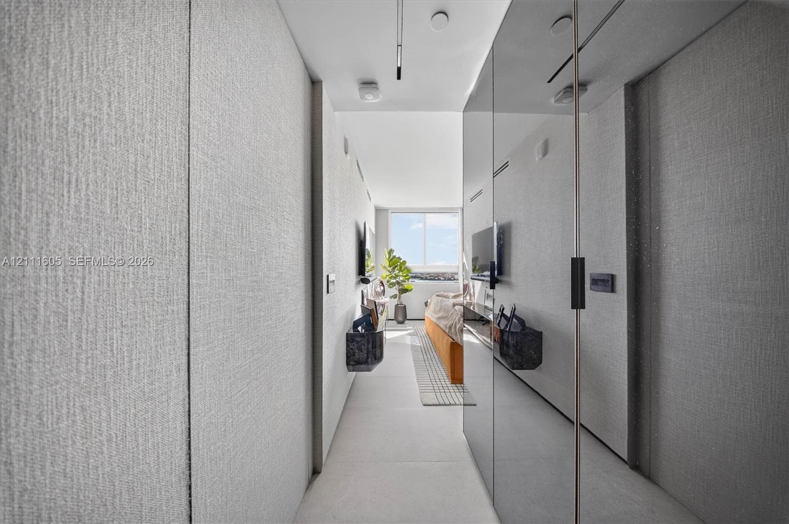 Full-height wall panels with textured light-gray finish, floor-to-ceiling mirror-finish cabinetry, porcelain tile flooring, and integrated ceiling track lighting