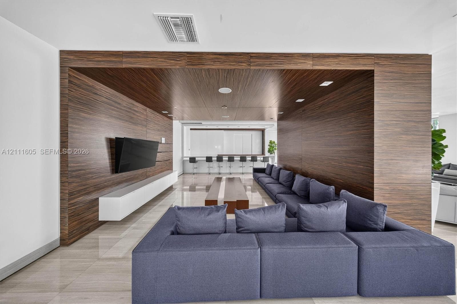 Interior space featuring floor-to-ceiling wood paneling, recessed lighting, polished stone tile flooring, a wall-mounted floating cabinet, and a built-in refreshment bar
