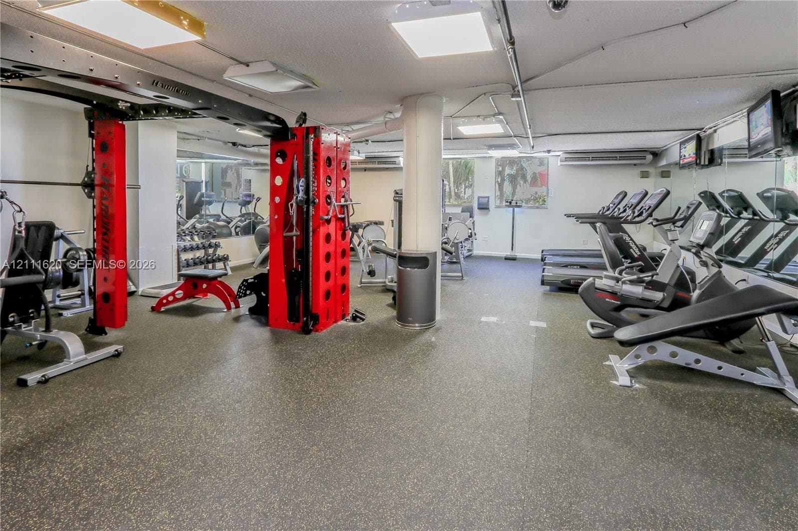 Fitness facility featuring wall-to-wall mirrors, recessed lighting, and resilient rubberized flooring
