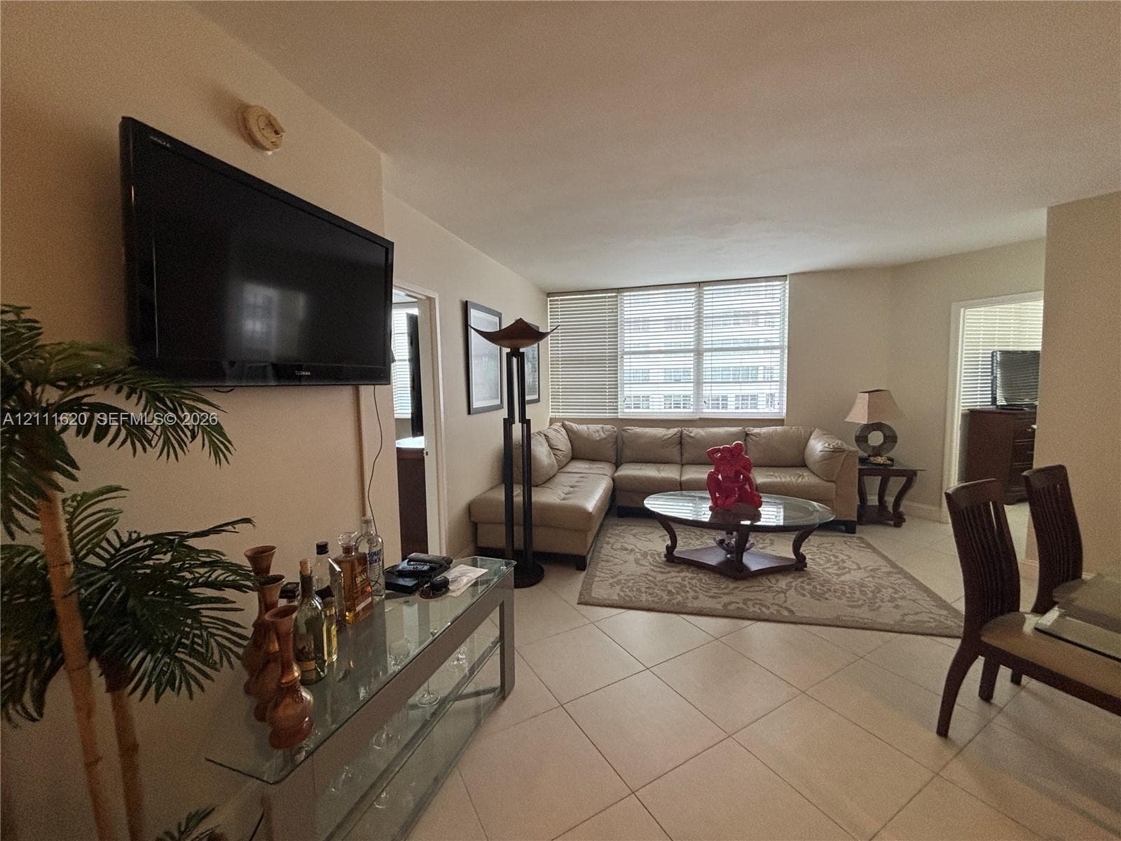 Neutral-toned tile flooring, large multi-pane windows with horizontal blinds, and smooth-finish walls