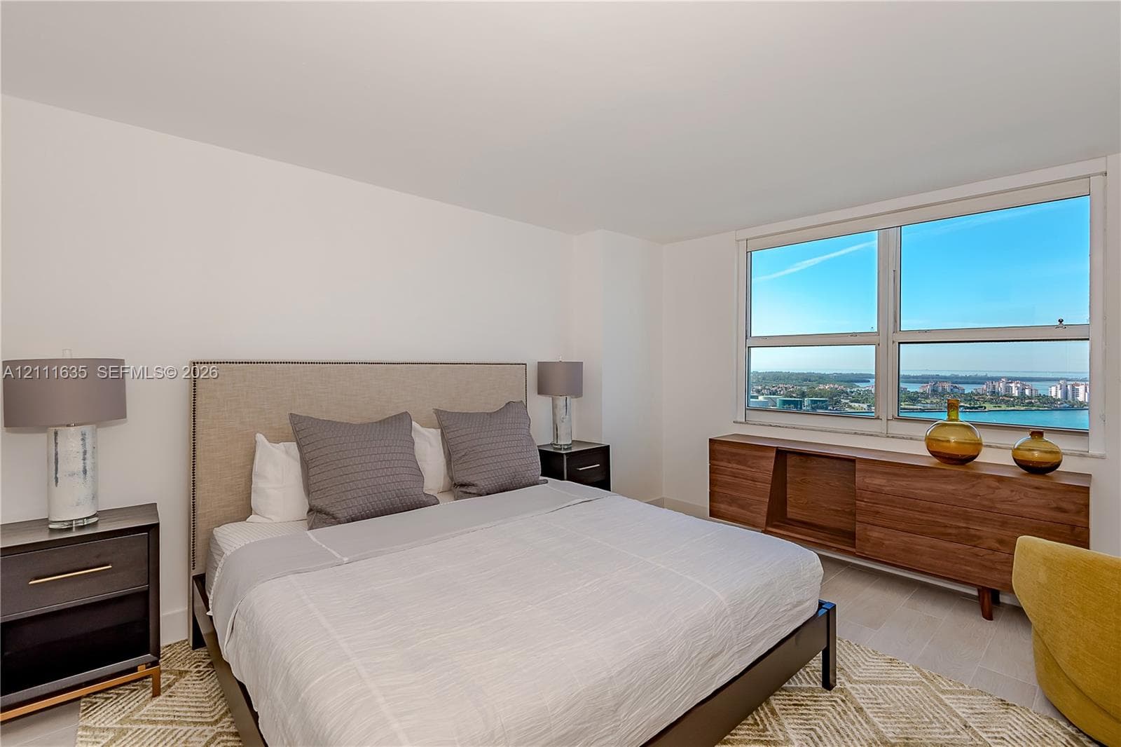 Bedroom featuring large format windows, wood-finish flooring, and neutral wall paint