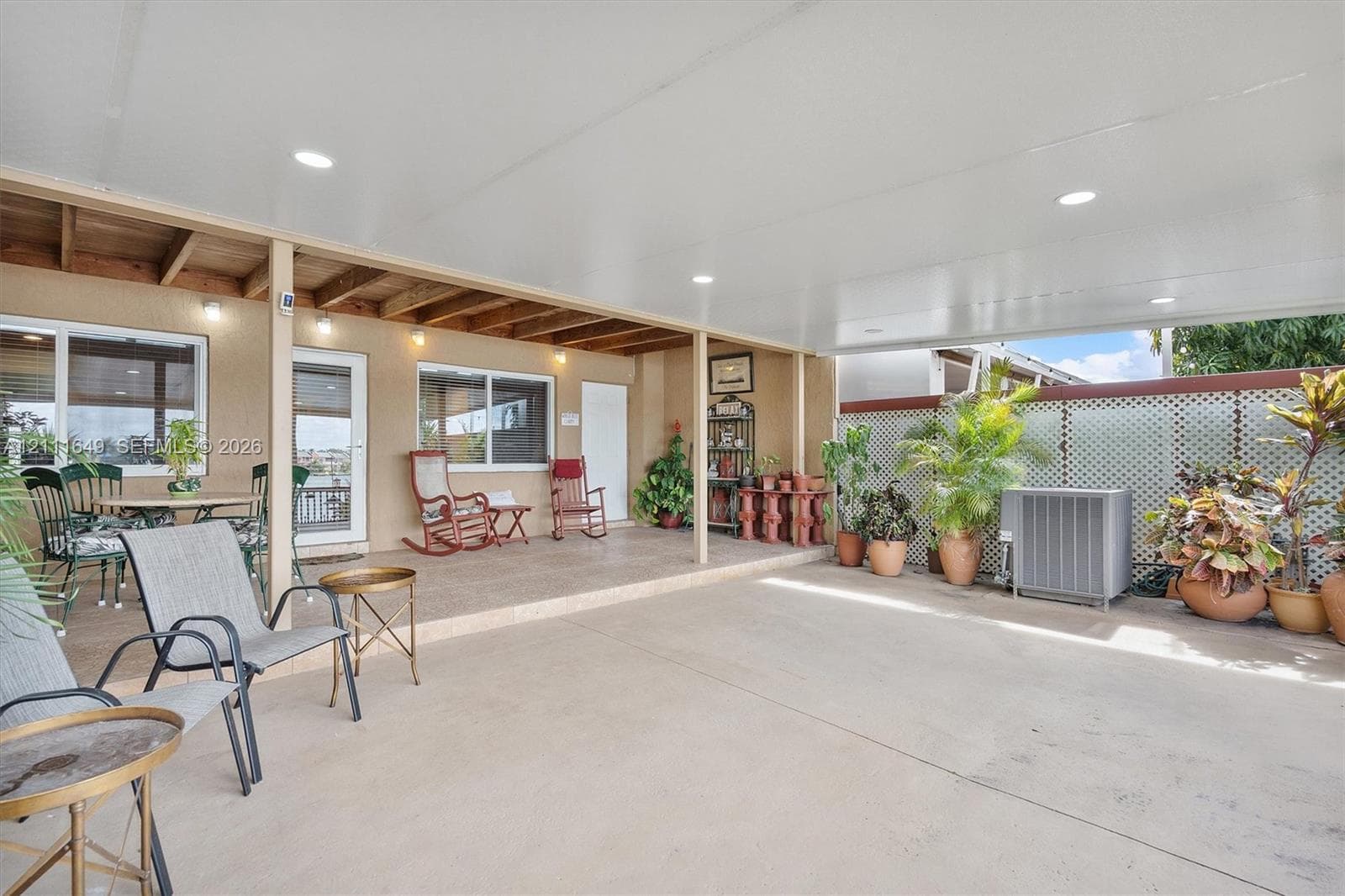 Covered patio featuring an expansive concrete surface, recessed lighting, exposed wood ceiling beams, and decorative lattice wall paneling