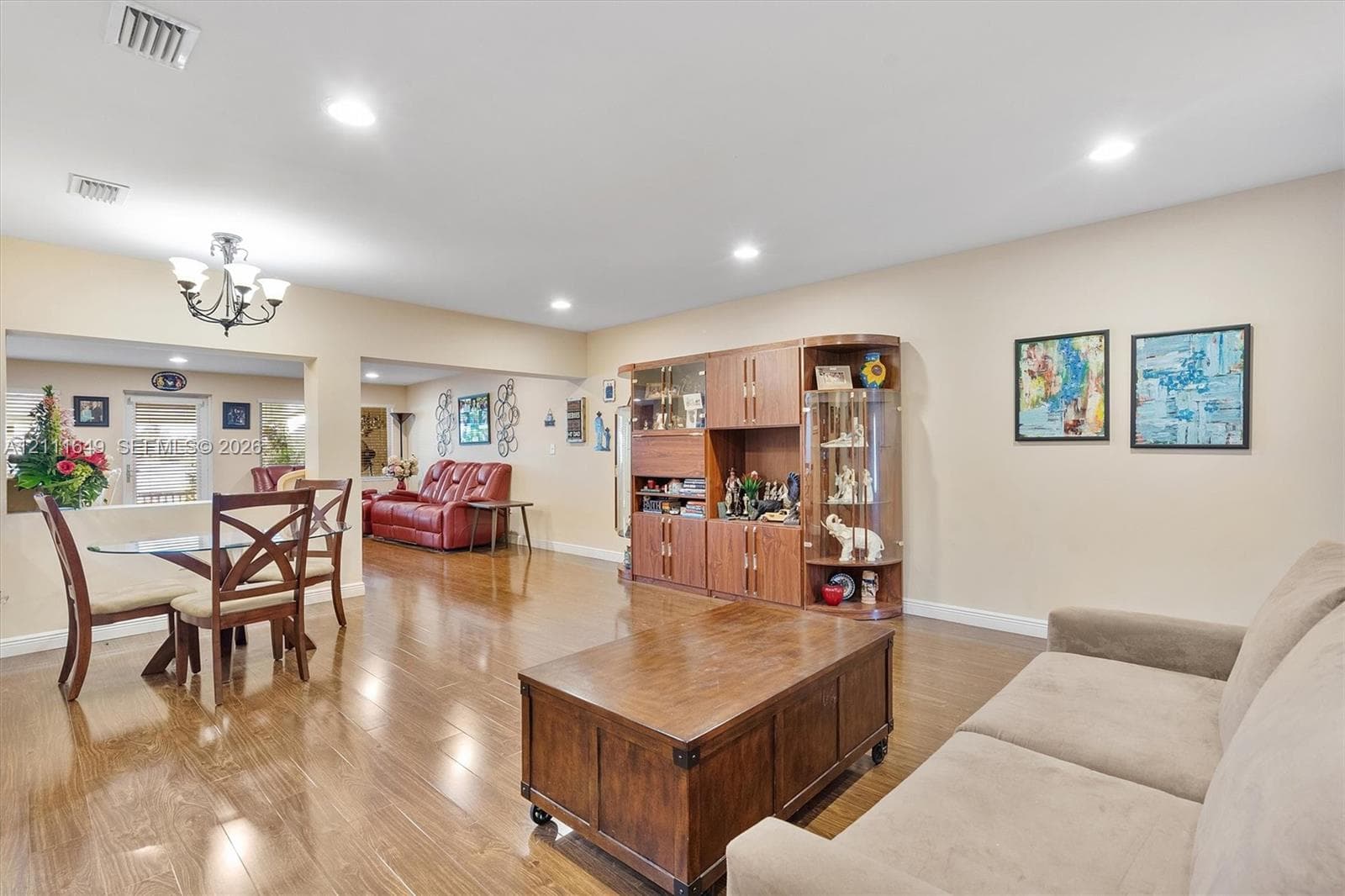 Open-concept interior featuring wood-finish flooring, recessed lighting, and built-in cabinetry with glass-front display shelving