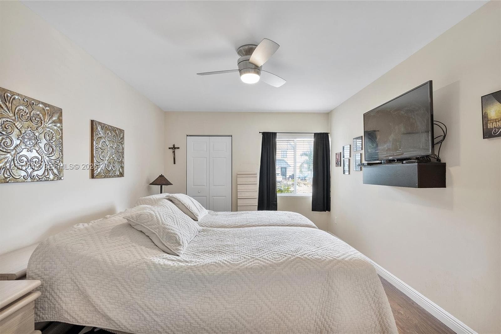 Bedroom featuring wood-finish flooring, a ceiling fan with integrated lighting, and a dual-panel closet door