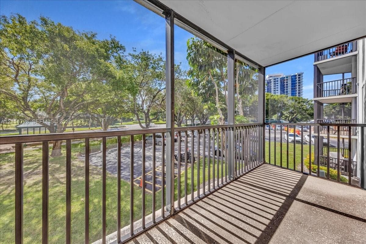 Screened-in balcony featuring metal railings and concrete flooring