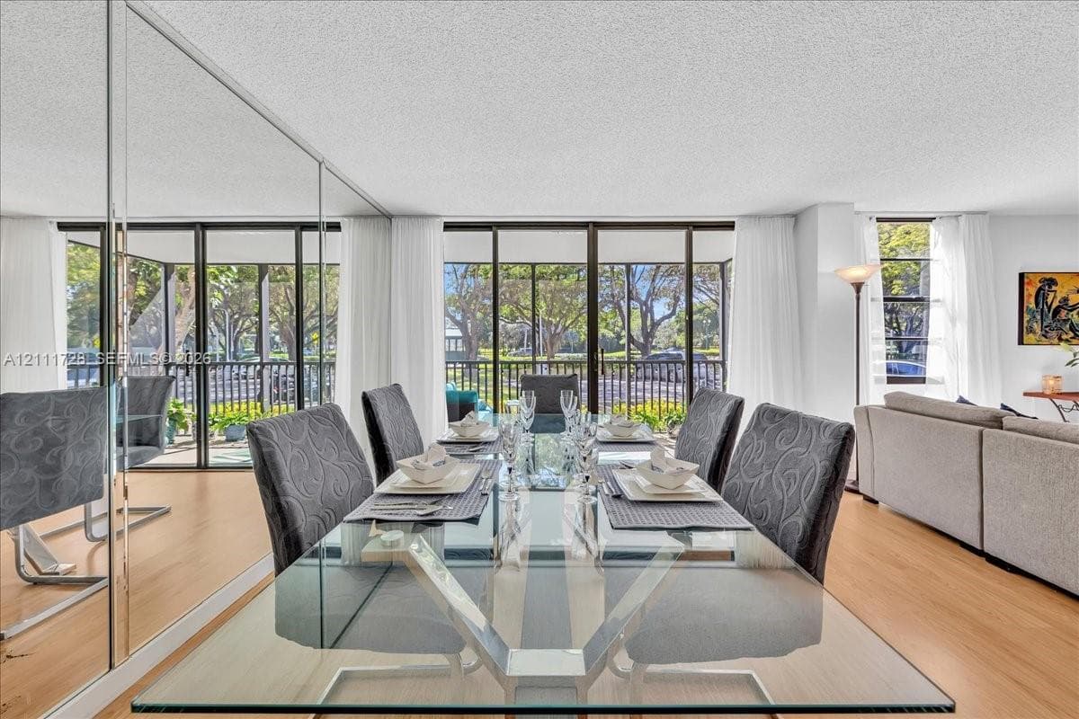 Floor-to-ceiling mirrored wall, wood-finish flooring, and expansive glass sliding doors featuring screen enclosures