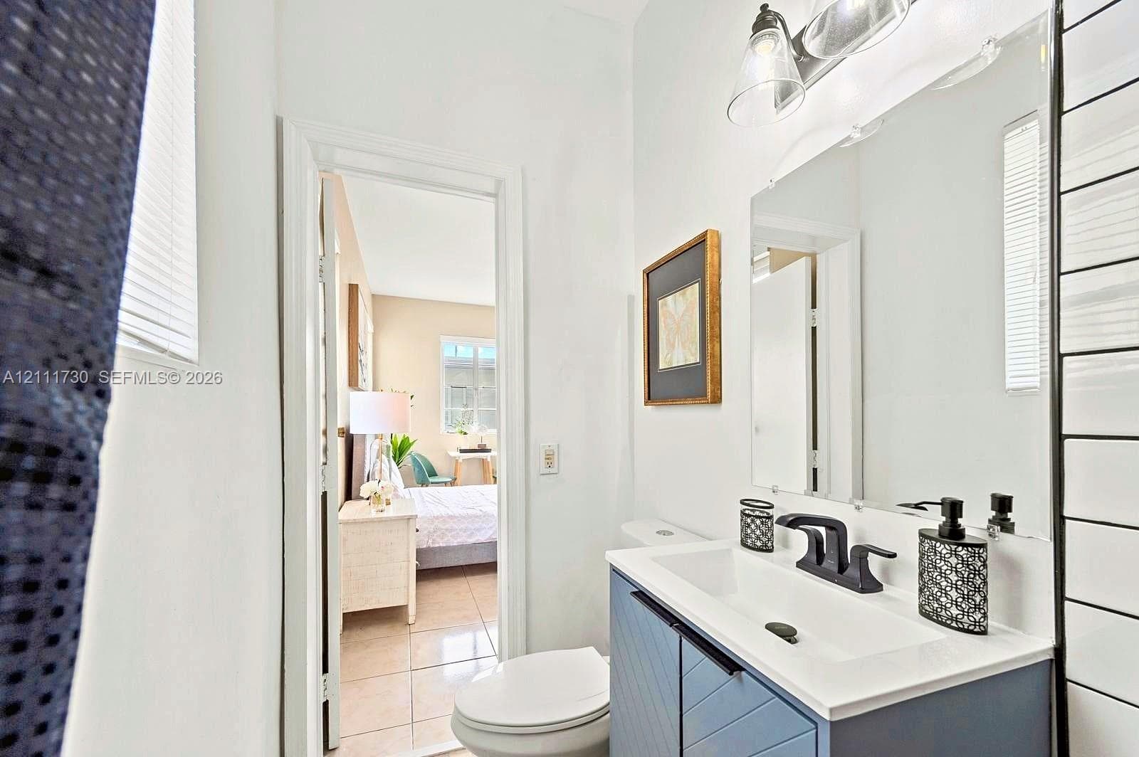 Blue vanity with chevron-patterned cabinet doors, rectangular integrated sink, matte black faucet, wall-mounted mirror, and glass-shaded lighting fixture