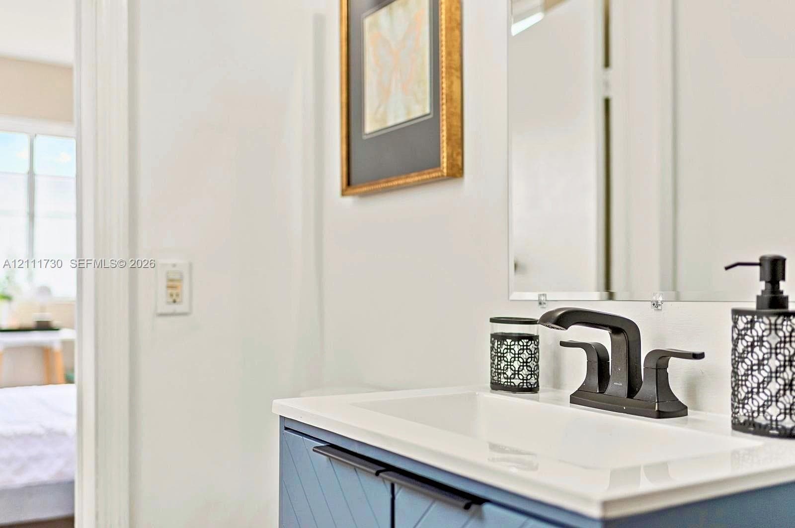 Blue vanity with chevron-patterned cabinetry, matte black hardware, integrated rectangular sink, and wall-mounted mirror