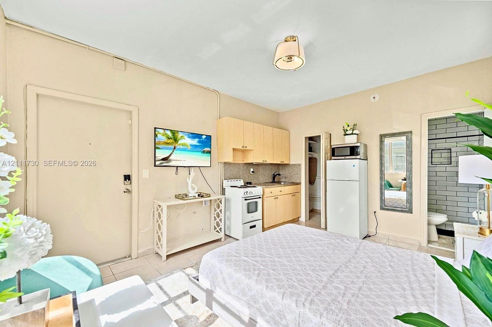 Kitchenette featuring light wood cabinetry, integrated sink, and white range