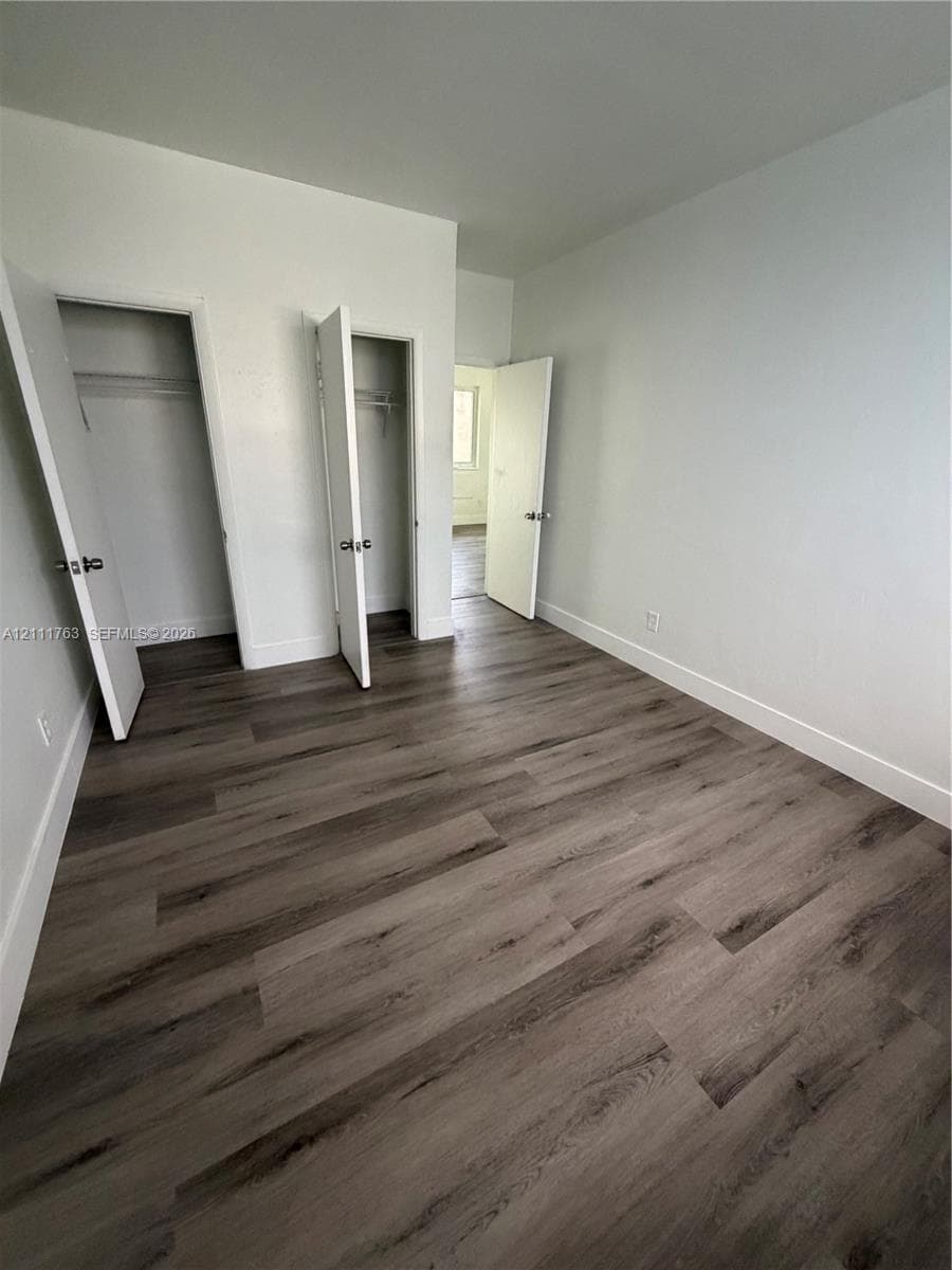 Wood-finish flooring, neutral wall tones, and dual closets with swinging doors