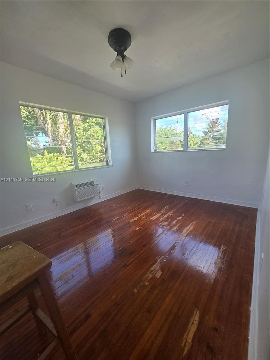Interior room featuring wood-finish flooring, two multi-pane windows, and a ceiling-mounted light fixture