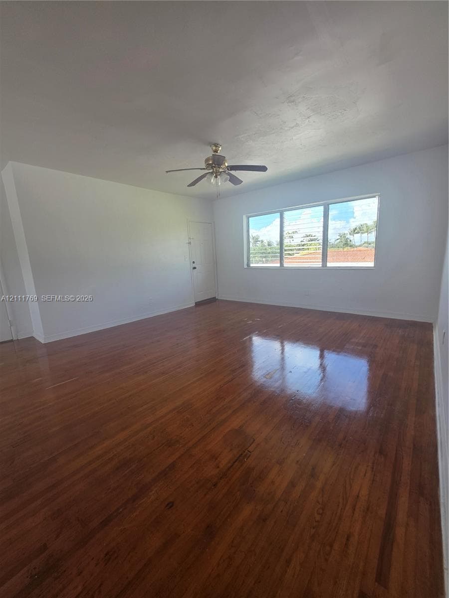 Interior space featuring wood-finish flooring, a multi-pane horizontal window, and a ceiling-mounted fan with integrated light fixture