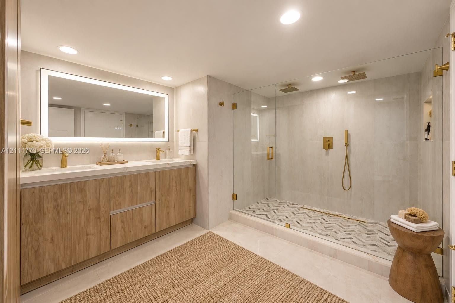 Dual vanity with wood-finish cabinetry, quartz countertops, integrated LED-backlit mirror, and gold-toned fixtures