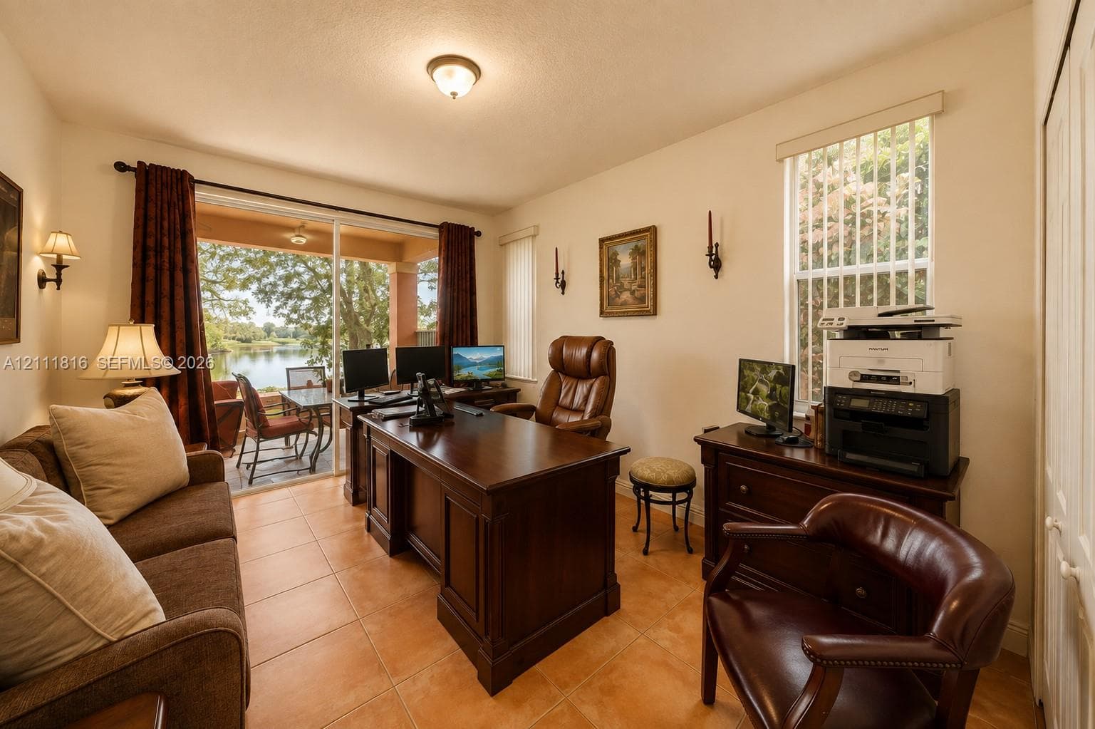 Interior space featuring neutral wall paint, tile flooring, wall-mounted light fixtures, vertical window blinds, and large sliding glass doors providing outdoor access