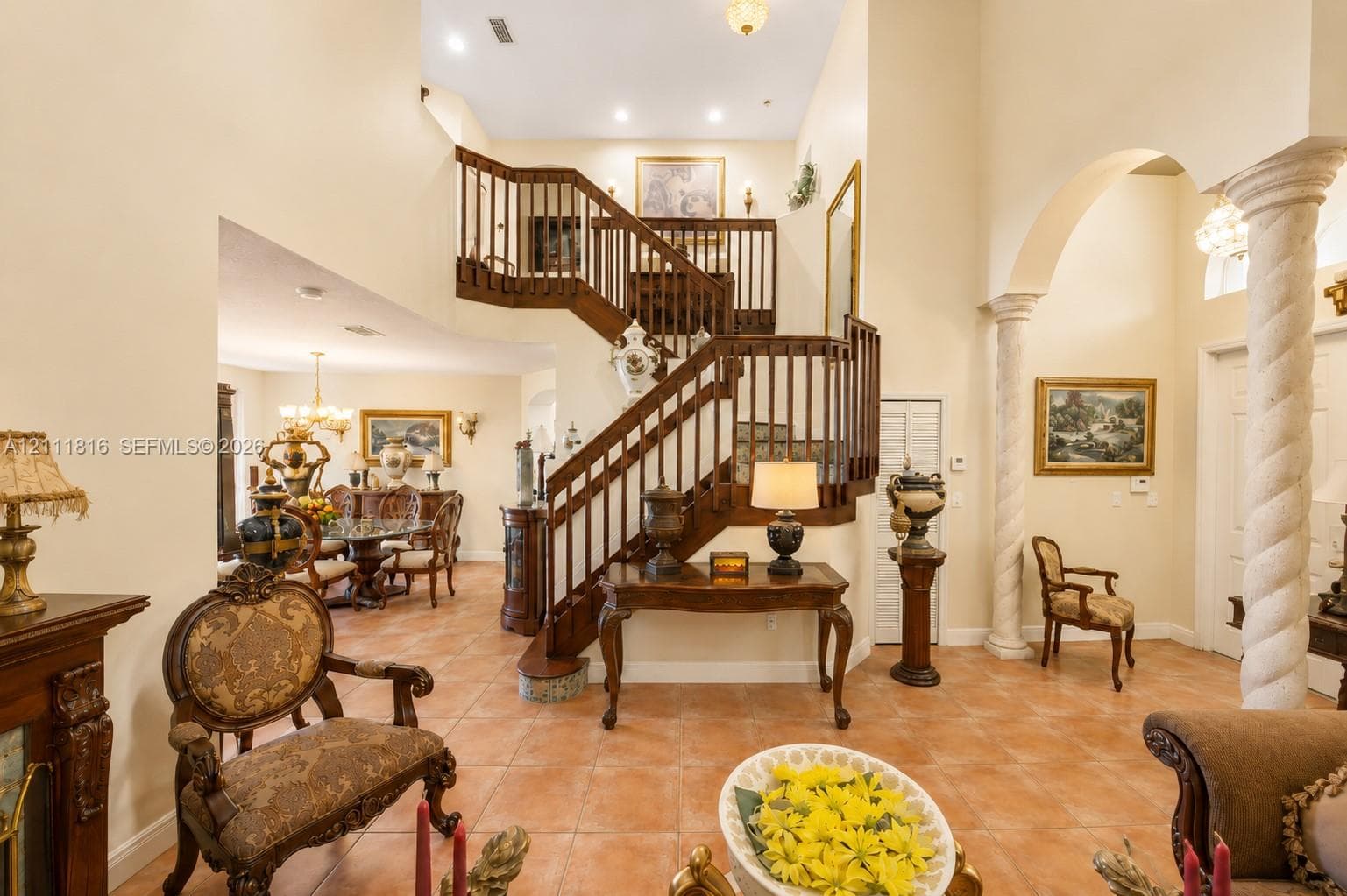 Foyer featuring a multi-story ceiling, decorative columns, tile flooring, and an open staircase with wood railings