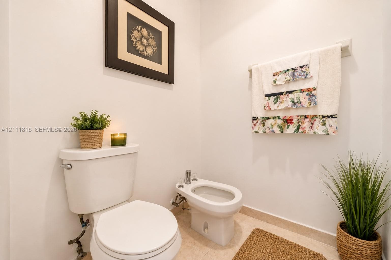 White ceramic toilet and matching bidet with chrome fixtures, complemented by light-toned tile flooring