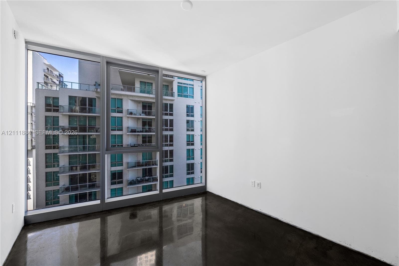 Floor-to-ceiling windows with dark framing, polished concrete flooring, and neutral white walls