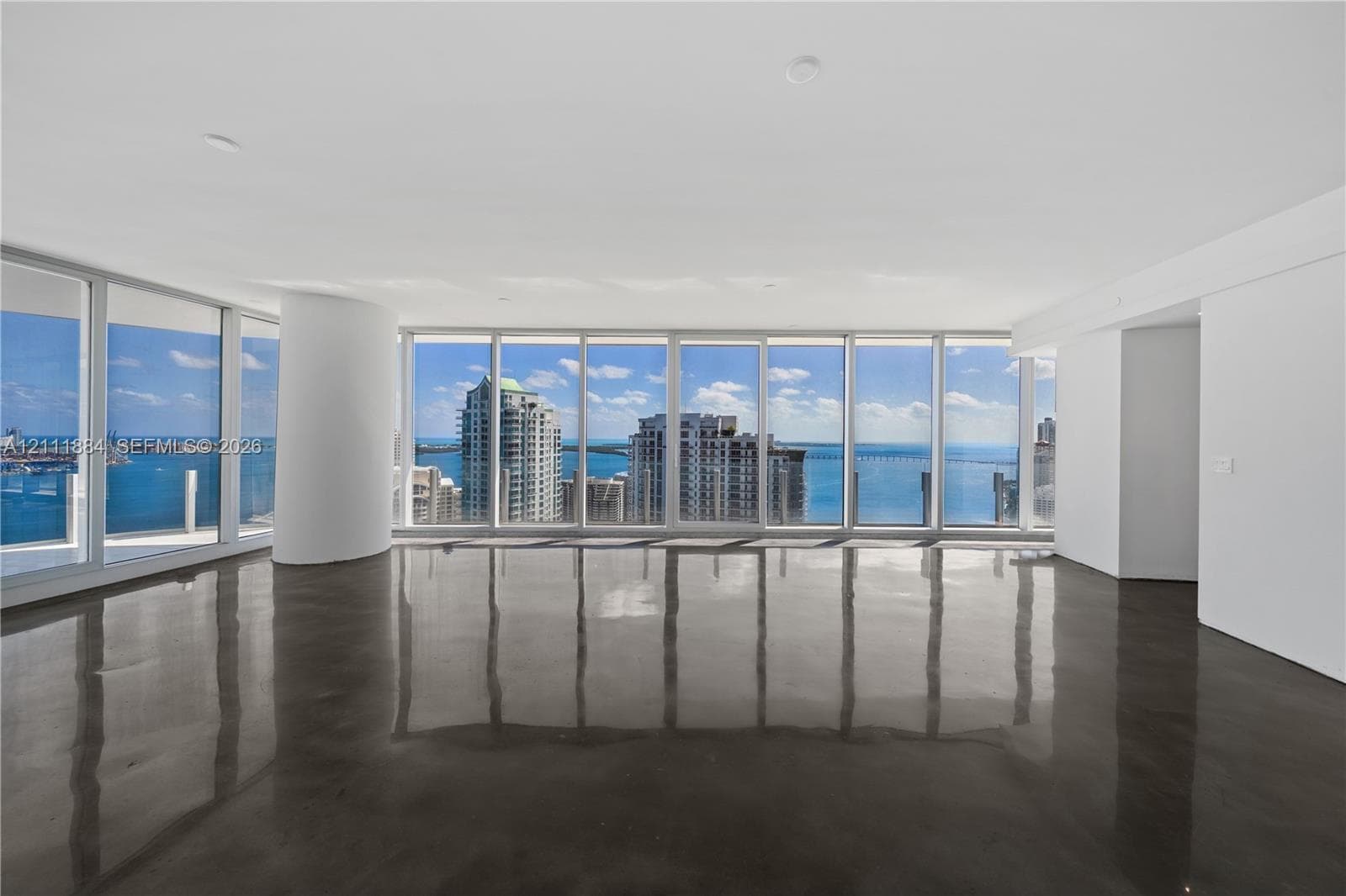 Open-concept interior featuring floor-to-ceiling glass walls, polished concrete flooring, recessed lighting, and a structural column