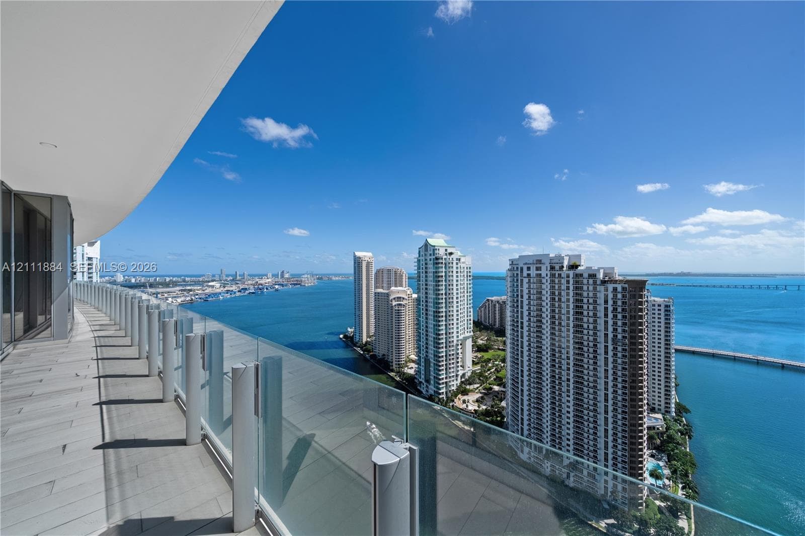 Expansive wrap-around balcony featuring large-format tile flooring and frameless glass railings