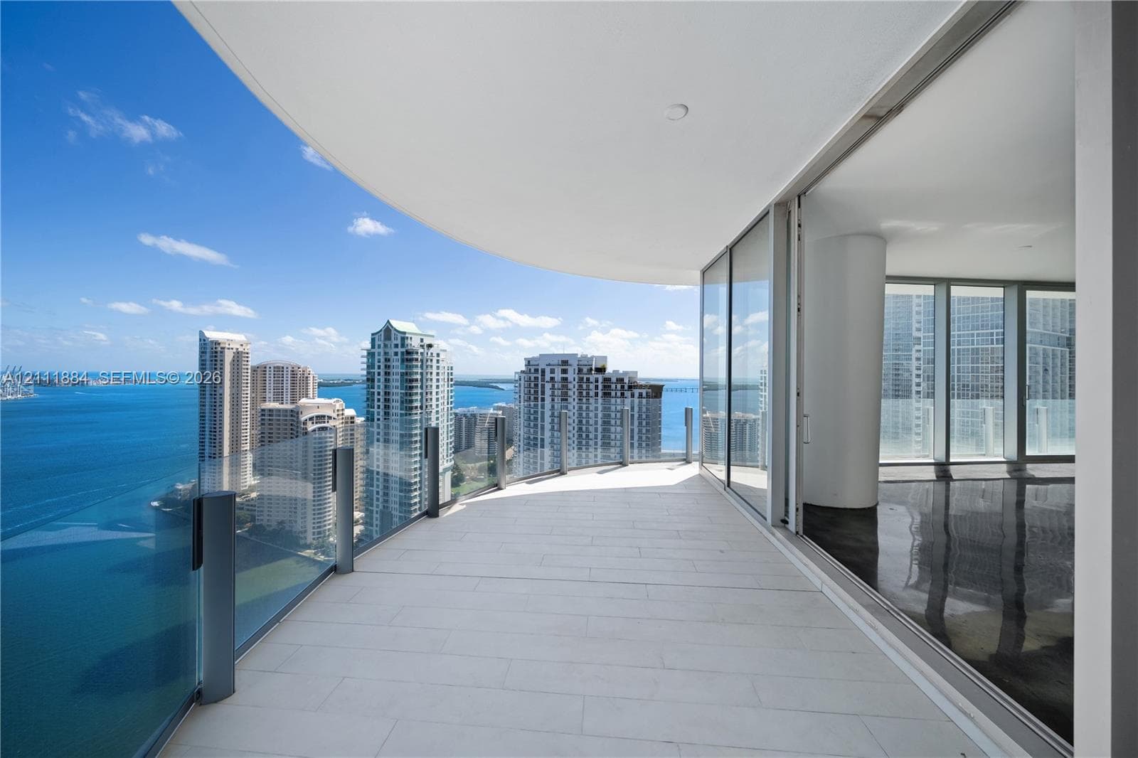 Wraparound balcony featuring large-format tile flooring, a glass panel railing, and expansive floor-to-ceiling glass sliding doors