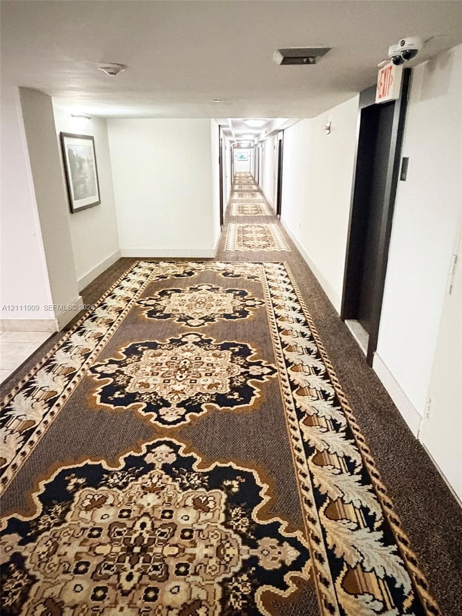 Hallway featuring patterned carpet flooring, recessed ceiling lighting, and a metal elevator door