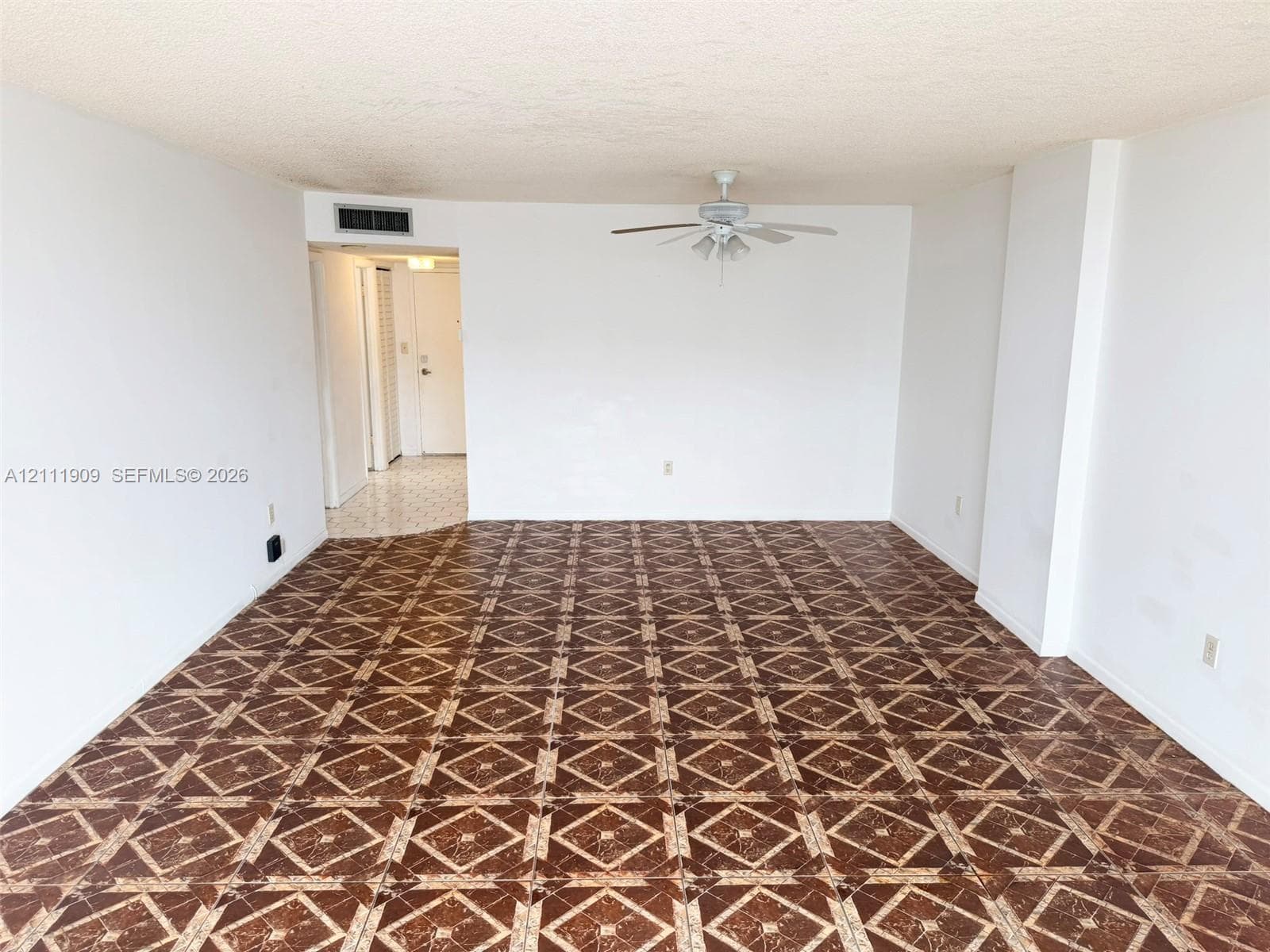 Spacious interior featuring patterned tile flooring, a centered ceiling fan with integrated lighting, and neutral wall finishes
