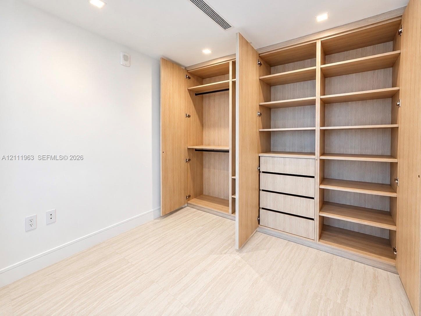 Custom built-in closet featuring light wood-finish cabinetry, adjustable shelving, integrated drawer storage, and recessed ceiling lighting