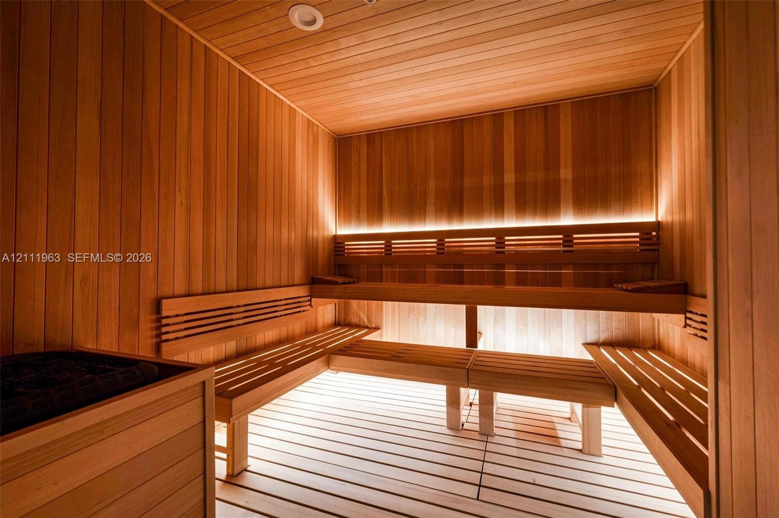 Sauna featuring full wood-panel cladding, multi-level slatted wood bench seating, integrated LED accent lighting, and a built-in heating unit