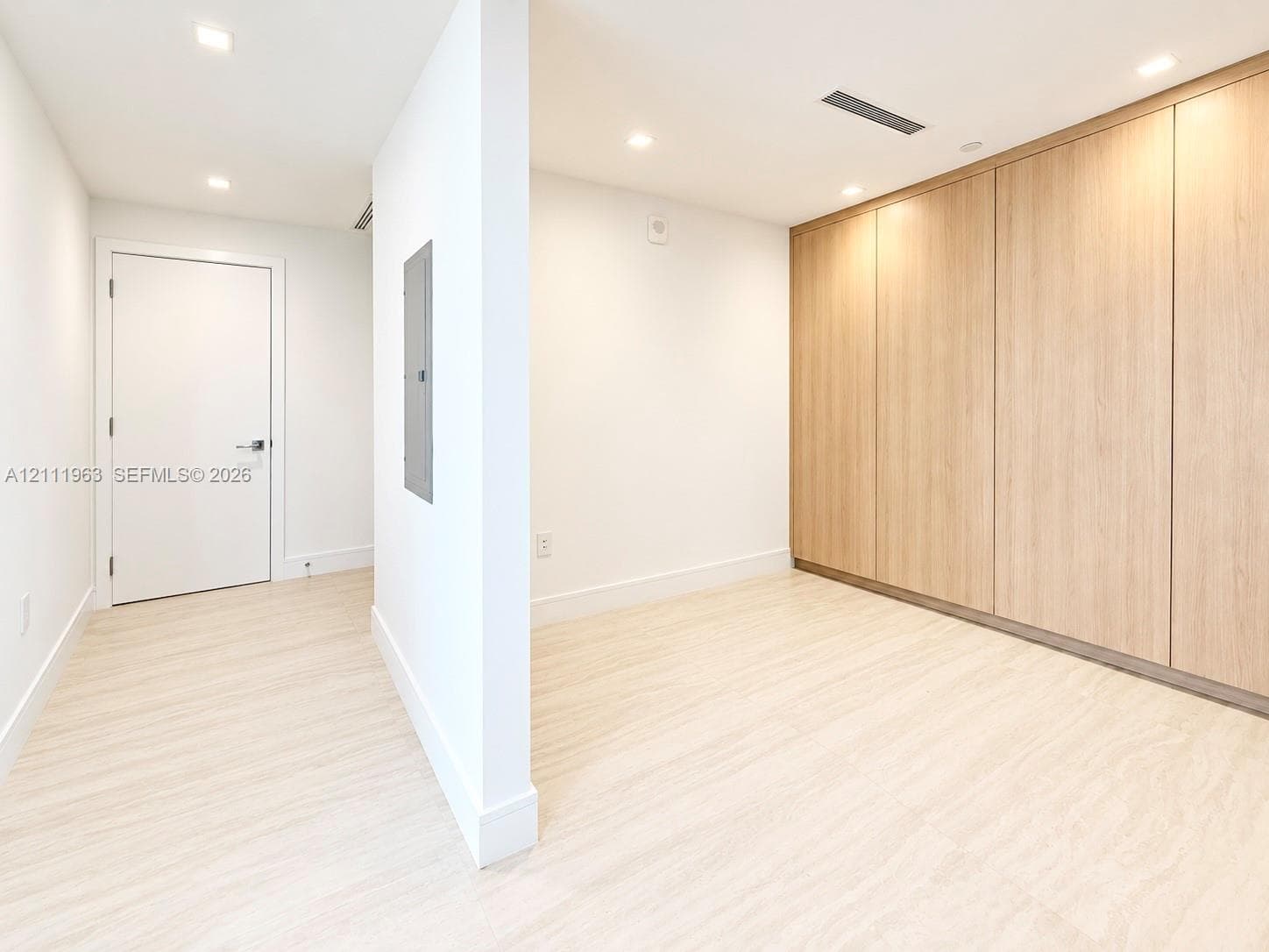 Interior space featuring light-toned wood-finish flooring, recessed ceiling lighting, and floor-to-ceiling built-in wooden cabinetry
