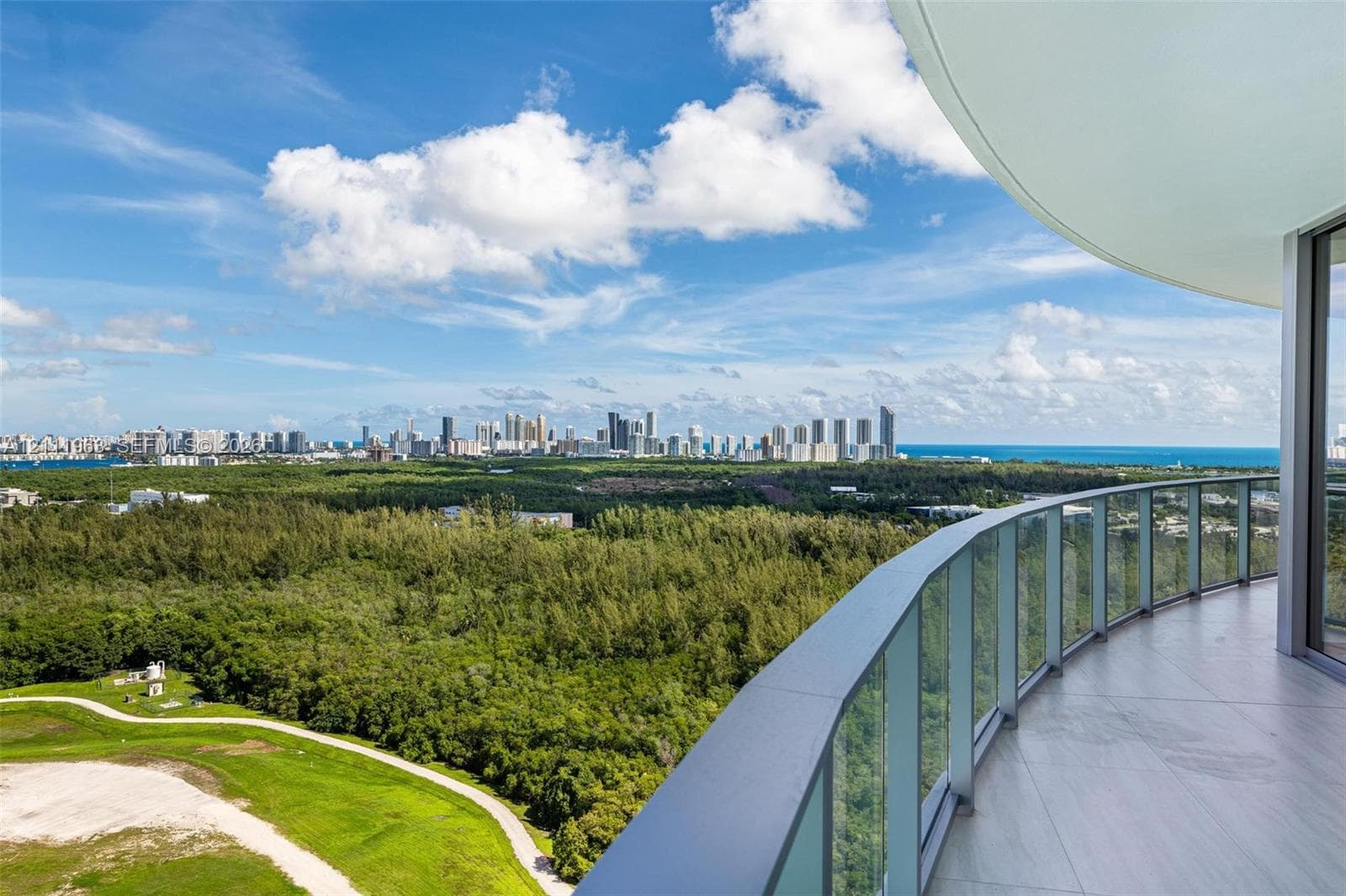 Curved balcony featuring tile flooring and a glass panel railing