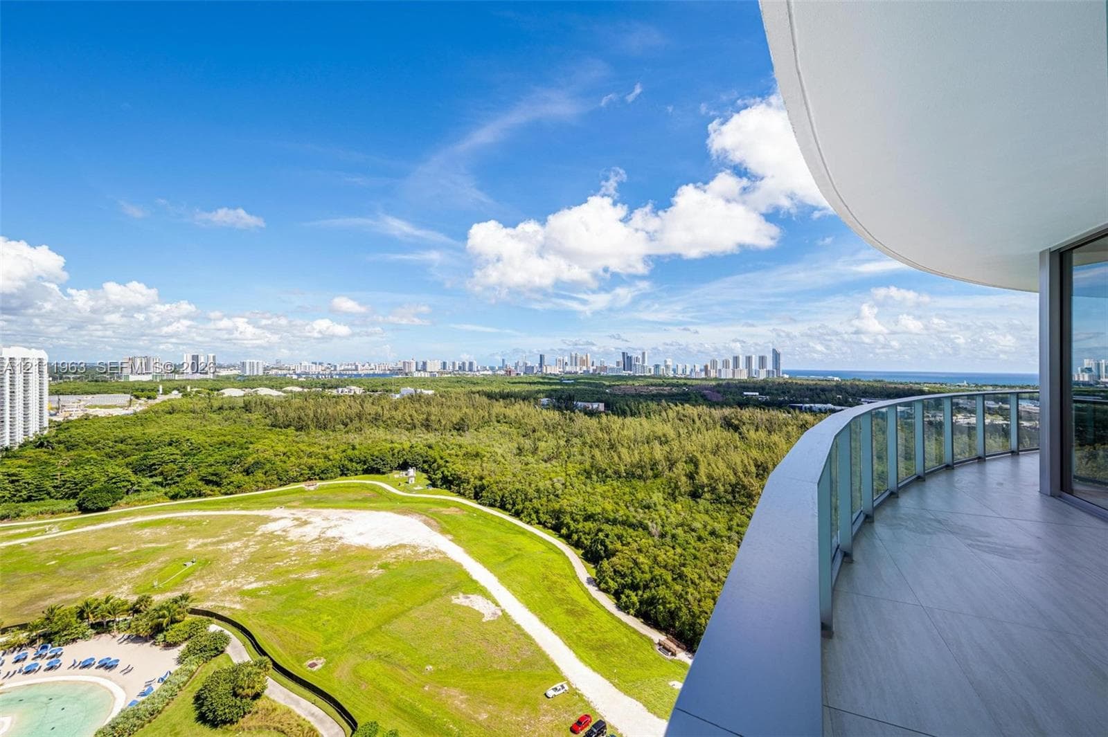 Curved balcony featuring large-format porcelain tile flooring and a glass panel railing