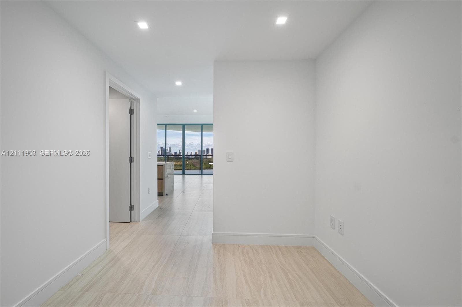 Interior space featuring neutral white walls, recessed ceiling lighting, and large-format tile flooring